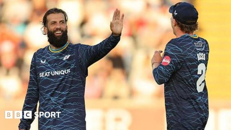 Yorkshire player Moeen Ali smiles and holds up his hand in celebration as he is approached by team-mate Dom Bess.