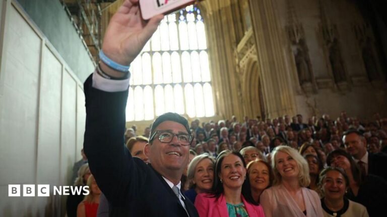 Who could be the UK’s next chancellor? Andy Burnham wearing a black suit, white shirt, and grey tie taking a selfie of a large crowd of Labour MPs in Westminster on the day he is sworn in as an MP