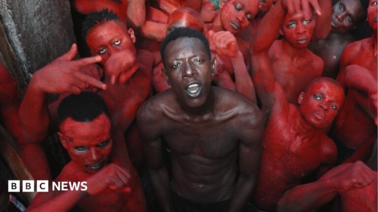 Jail Time Records: The notorious Cameroonian prison with its own record label A topless Empereur stands in the centre of a group of young men, who are painted in red.