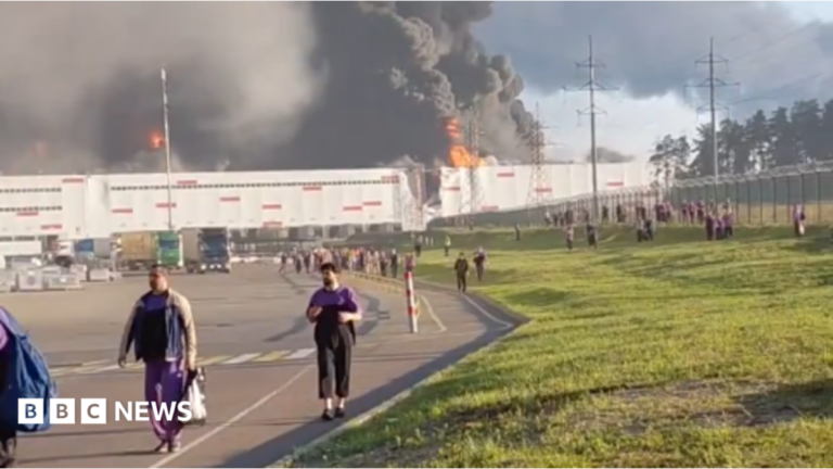 Russian online retail warehouses hit by deadly Ukrainian strikes people walk away from a burning warehouse