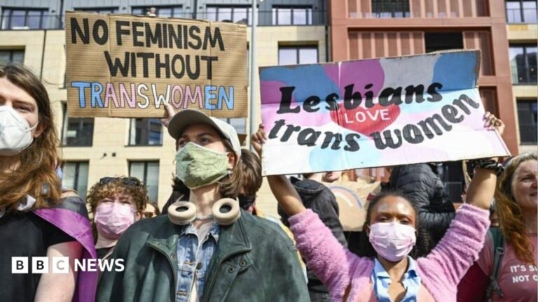 Unions to boycott Labour women’s conference over trans ban A group of protesters hold up placards. One reads "No feminism without trans women". Another reads "lesbians love trans women" and is being held up by a woman wearing a pink cardigan and a pink face mask.