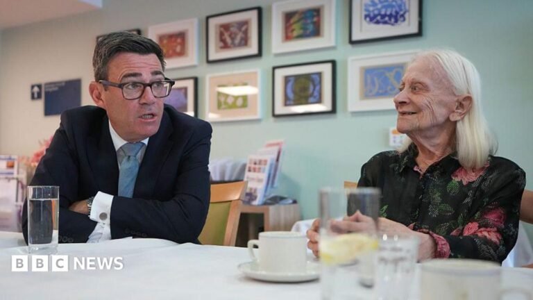 AI will not solve cash crisis for UK councils, warn experts Andy Burnham sits at a table in a care home, talking face-to-face with a resident. The prime minister is in a dark suit and glasses and leans forward while speaking, and the other, with long white hair, sits opposite. Several glasses of water and cups are on the table, with framed artwork displayed on the wall behind them.