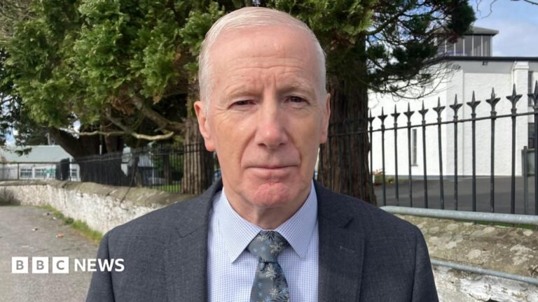 DUP MP Gregory Campbell to face expenses probe A man stands close to the camera, with short white hair, wearing a grey suit and blue shirt.