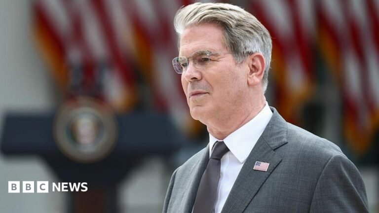 Iran faces ‘greatest financial offensive ever’, says US Treasury Secretary Scott Bessent US Treasury Secretary Scott Bessent's head and shoulders in profile. He has grey hair and glasses. He is wearing a grey suit with a US flag lapel pin, a silver tie, and a white shirt. Behind him in soft focus are US flags and a podium.