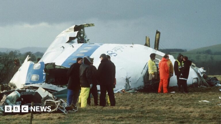 Emergency service workers stand next to the wreckage of Pan Am flight 103 in a field east of Lockerbie.