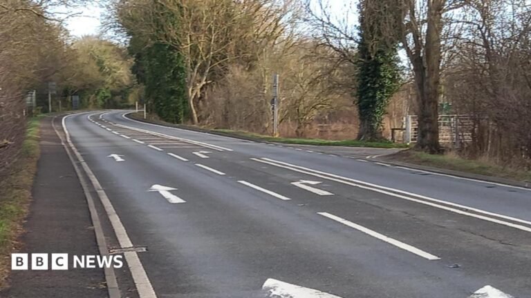 Man dies in crash after Stratford-upon-Avon police pursuit An A road, with road markings pointing straight ahead and right. Bare trees line the road on either side side