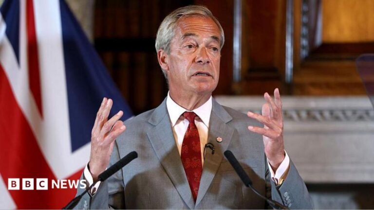 Send foreign prisoners abroad to end early releases, says Reform UK Nigel Farage at a press conference on Monday. He is standing at a podium with the words "Reform UK". Both of his hands are in the air. In the background is a UK flag.