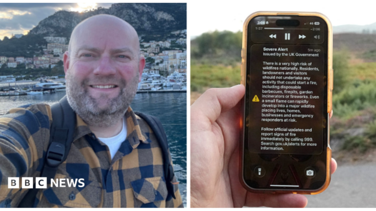 Serious questions over use of UK emergency alerts, its creators say A man holds a phone in front of a green field. The phone is displaying the UK government wildfire alert.
