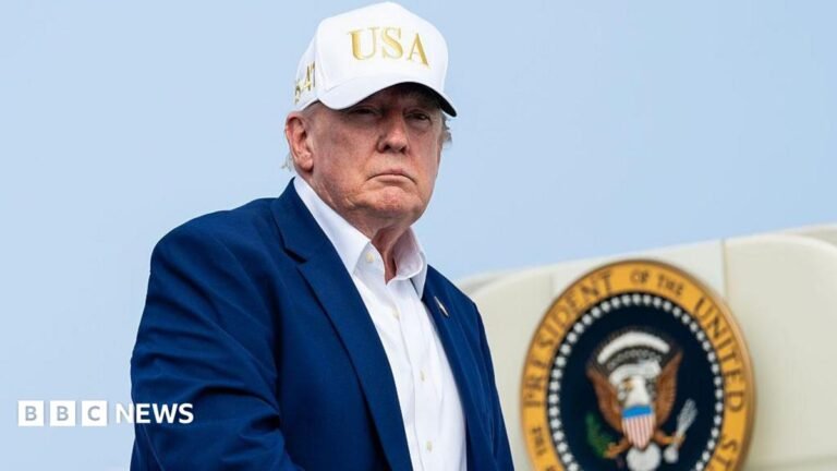 Trump threatens ‘tremendous economic consequences’ on any country helping Iran Trump, wearing a suit and no tie and a white "USA" hat, descending from airplane steps