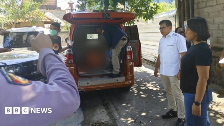 A person stands inside the rear end of an orange van while several other people stand beside the vehicle