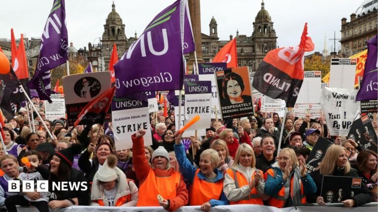 Glasgow City Council to fire and re-hire over 23,000 employees A large group of women stand behind a banner that reads 'Glasgow Equal Pay'. They are wearing orange high visibility vests and standing with their arms raised, shouting and waving Unison flags. In the background is the Glasgow City Council building in George Square.