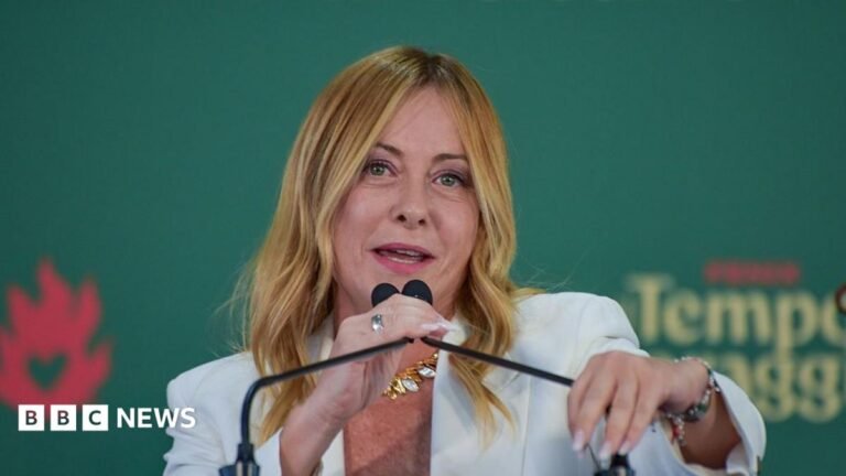 Italy ministers agree to ban burqa and niqab in school and cap foreigners in class Italian Prime Minister Giorgia Meloni, who has long blonde hair and is wearing a white jacket, speaks into a microphone at an event on 20 September.