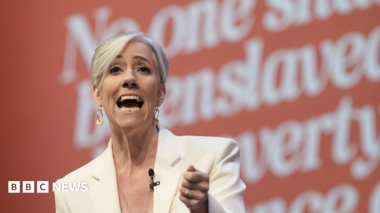 Lib Dem Daisy Cooper vows to end ‘computer says no’ economy to boost growth Head and shoulders shot of Cooper wearing a white suit over a white top. She has short blonde hair with a long, asymmetrical fringe.