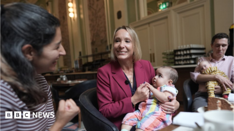 Lib Dems demand action over increase in child birth injuries Helen Morgan is in the centre of the picture, smiling and holding a baby on her lap. Morgan has a blonde bob and is wearing a berry-coloured jacket over a navy top. She is looking at a woman in a stripy top on the left and a man holding another baby is on the right.