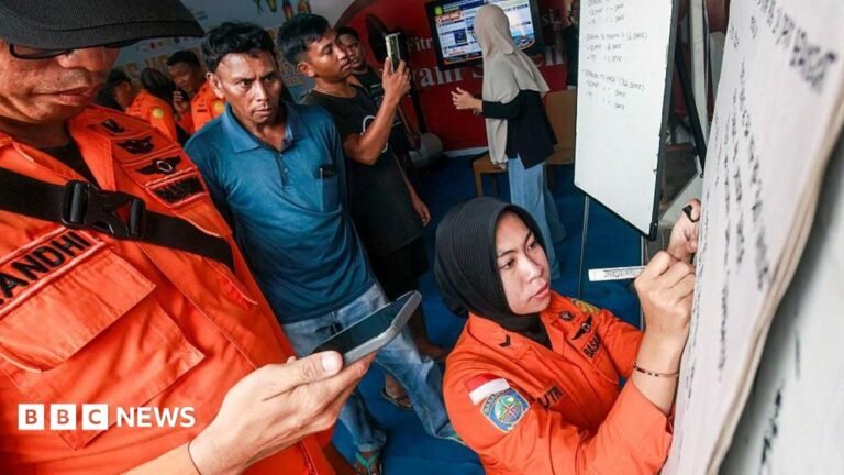 Relatives of affected passengers look on as a National Search and Rescue Agency (Basarnas) officer writes updates on a whiteboard amid ongoing rescue operations on the stricken Virgo Transport 8 ferry, at Trisakti Bandarmasih Port in Banjarmasin, South Kalimantan, on September 13, 2026.