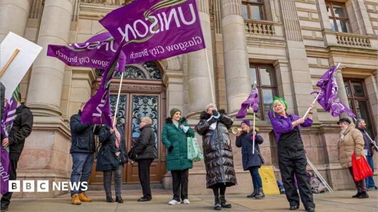 Scottish government urges council to pause fire and rehire plans a group of workers protesting and waving purple 'Unison' flags outside an Glasgow City chambers.