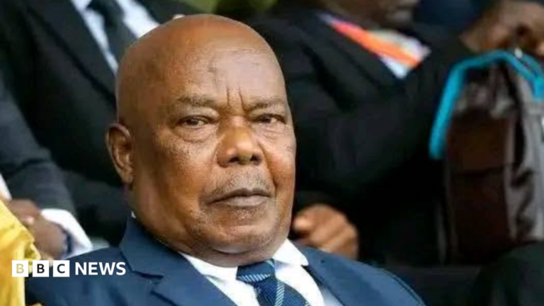 Tanzanian President Samia’s husband dies in hospital A woman with short reddish hair with a neutral expression faces the camera while sitting a room with black and brown wallpaper.