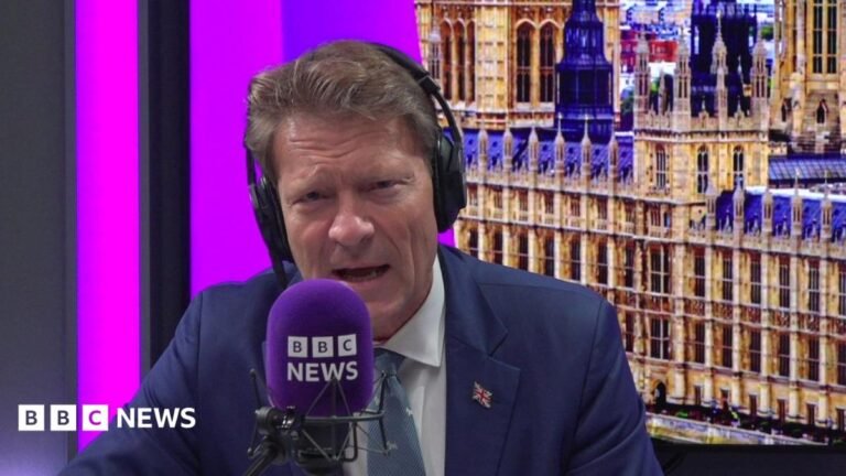 Tice defends Reform UK-led councils over tax rises and cuts Richard Tice, in blue jacket, white shirt, and black and white tie, points with his finger while talking to reporters