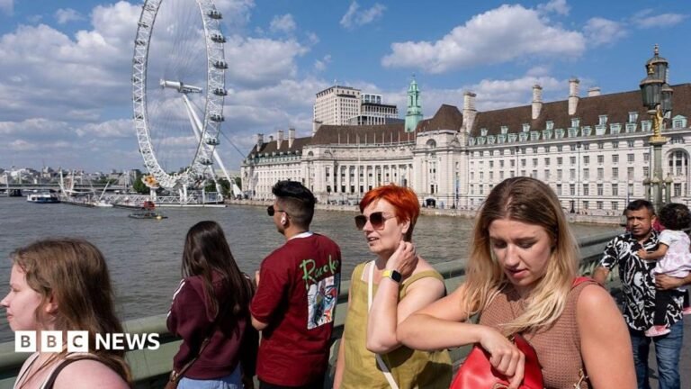 Tourists walking across Westminster Bridge in London with the London Eye in the background