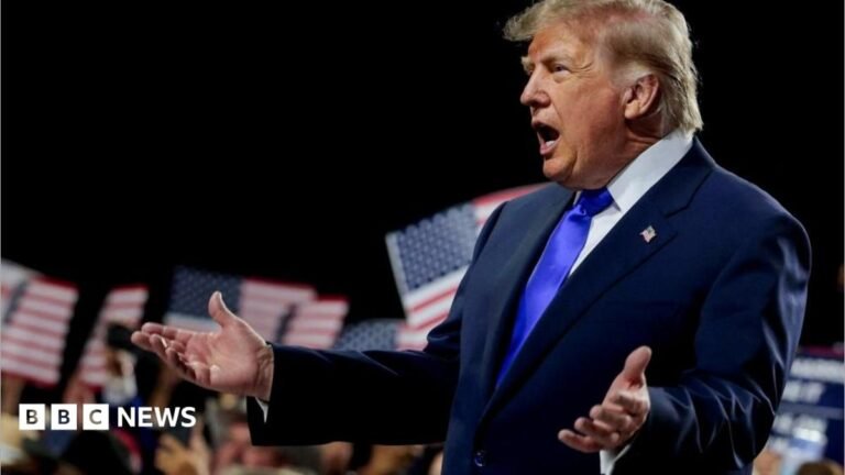 Trump wearing a blue suit and tie and white shirt opens his arms as he addresses the convention in Dallas