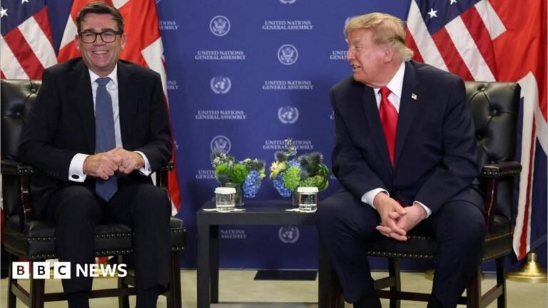 Trump says he can do business with Burnham but criticises ‘terrible’ Chagos deal Andy Burnham is sat on the left and Donald Trump on the right. Both men are wearing dark coloured suits and white shirts. Burnham has a blue tie and is wearing glasses, Trump has a red tie. Trump is looking at Burnham, who is laughing. There is a Union flag and US flag behind each man. The background is blue and has "United Nations General Assembly" written on it several times. There is a table between the two men. There are floral decorations and glasses of water on the table.