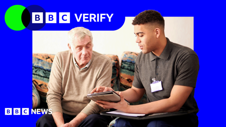 Will reforming the triple lock pay for social care reform? A senior man sat down speaking to a younger adult wearing a lanyard and holding a tablet.