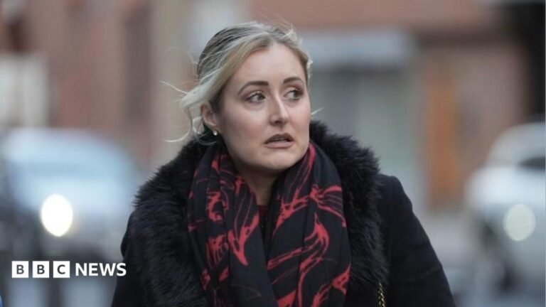 Katie Amess walking down the street wearing a red and black scarf and black coat