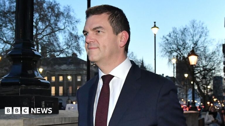 Ex-top official Olly Robbins reaches settlement with government over sacking Sir Olly Robbins walking down Whitehall wearing a suit and tie.