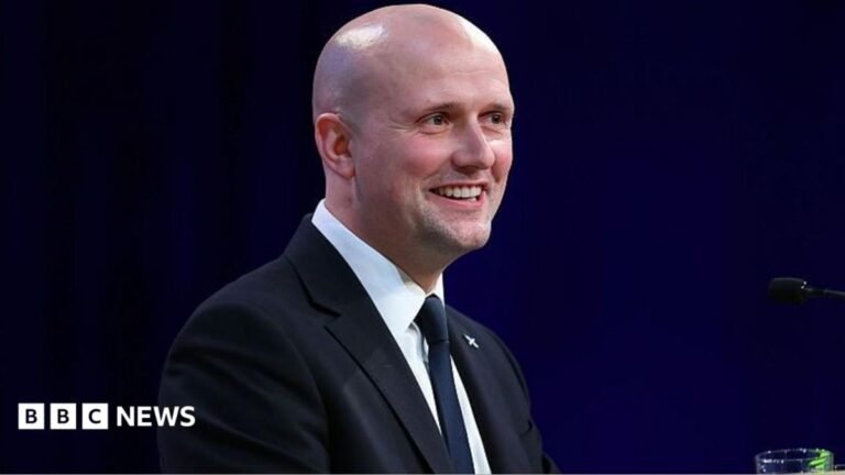 Flynn urges prime minister to ‘bring it on’ over independence referendum a bald man in a dark jacket, white shirt and dark tie is smiling as he gives a speech