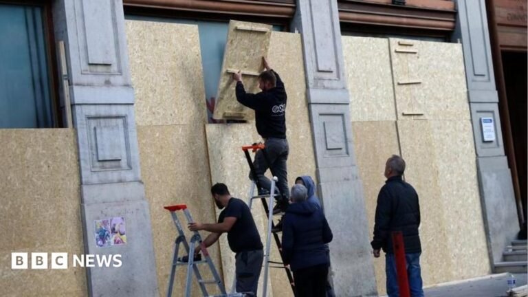 France prepares for day of protest a week after nationwide riots Large waves crashing over a black and white striped lighthouse at the end of a pier.