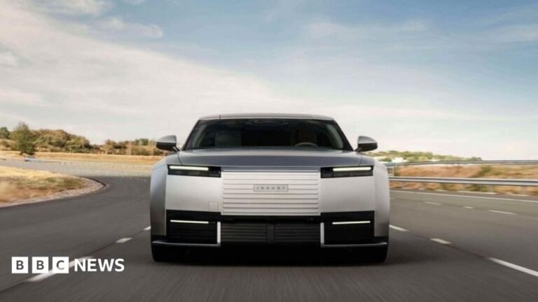 Jaguar launches new electric car after ‘woke’ ridicule A grey Jaguar car drives fast on a highway.