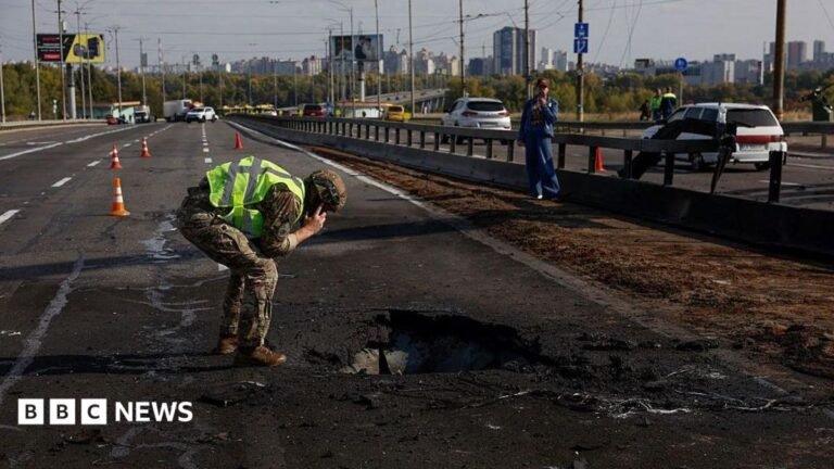 Kyiv bridge hit in further Russian drone attack as German chancellor makes surprise visit A white car drives next to a hole in the concrete road on the Pivnichnyi Bridge, which was hit by a Russian drone.