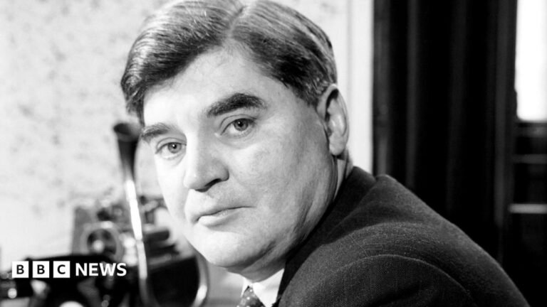 A black and white head and shoulders photo of Nye. He has short hair, with a side parting, and wears a suit, shirt and tie. He is looking at the camera with a serious expression.