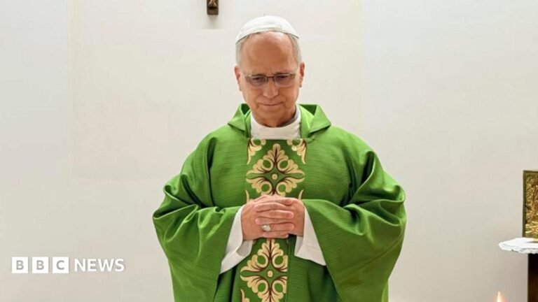 Pope pictured for first time since surgery and cancer diagnosis Pope Leo celebrates mass from hospital, wearing a green robe and standing before a white wall adorned with a wooden crucifix.