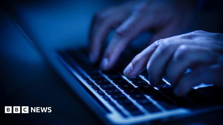 Hands close-up typing on a laptop keyboard in a blue light