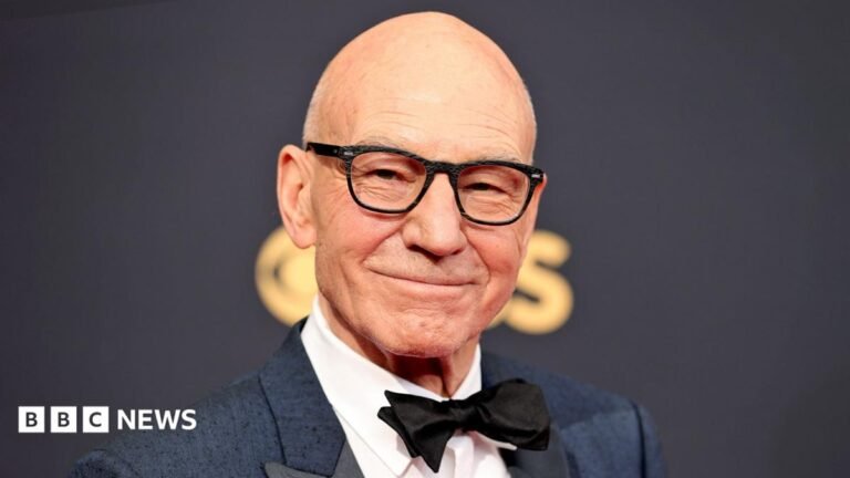 ‘Respected and beloved’: Tributes pour in for Sir Patrick Stewart Sir Patrick Stewart and William Shatner appear at a speaking event together in 2004. Both hold microphones and are wearing striped shirts.