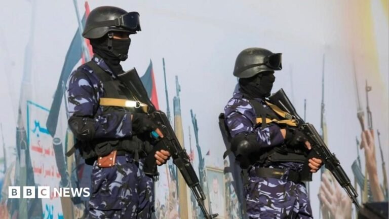 Riyadh airport attack another dangerous moment in already tense conflict Two soldiers with guns in blue camouflage standing guard in front of a big mural that has may pictures of guns on it.