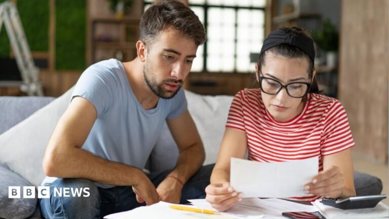 Tax thresholds remain unchanged – here’s what it means for your pay A young man and woman sit together on the sofa looking at paperwork