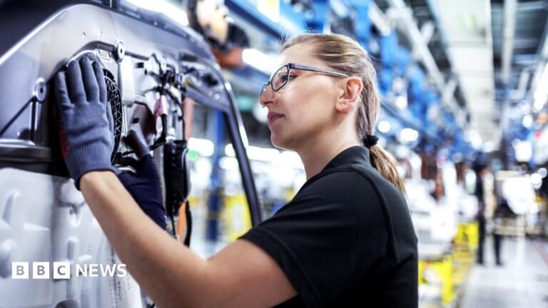 UK growth forecast upgraded but energy prices and rates to hit in 2027 A woman in a black t-shirt and wearing glasses and protective gloves works on a machine in a factory