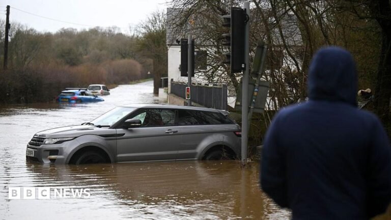 UK launch flood taskforce to prepare for extreme winter weather People look on at the cars stuck in the flooding in the hamlet of Weycroft, on January 27, 2026 in Axminster, England.
