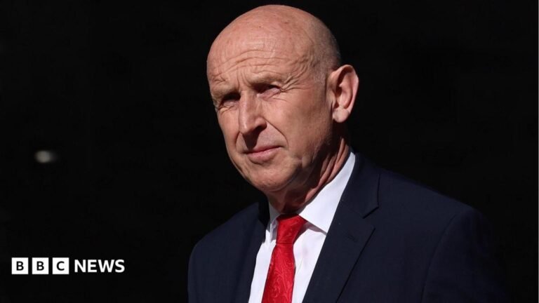 Who is new Chancellor John Healey? Labour veteran who quit as defence secretary A person wearing a hood, kicking the window of a shop front at night wile others look on.