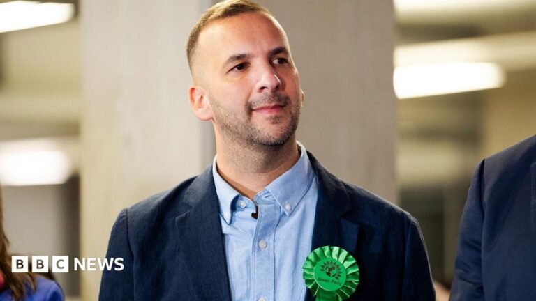 Zack Polanski to stay on as Green leader as crticism mounts Thin, red banner promoting the Politics Essential newsletter with text saying, “Top political analysis in your inbox every day”. There is also an image of the Houses of Parliament.